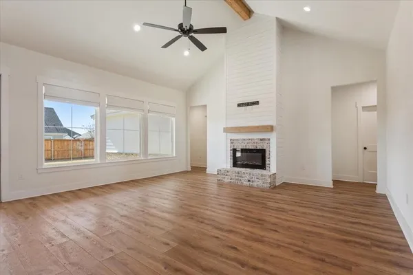 a view of an empty room with wooden floor fireplace and a window