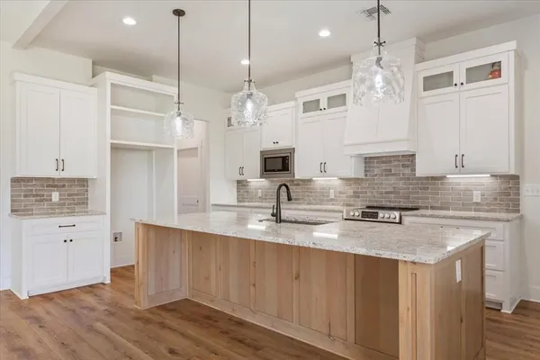 a kitchen with kitchen island granite countertop a sink cabinets and stainless steel appliances