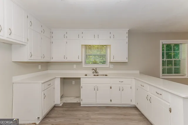 a kitchen with white cabinets appliances a sink and a window