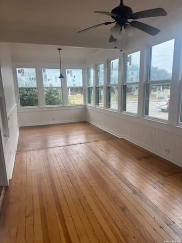 a view of an empty room with wooden floor and a window