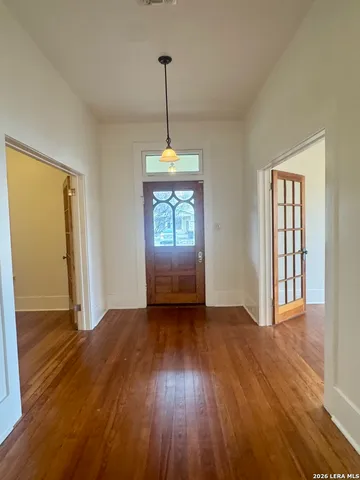 a view of an empty room with window and wooden floor