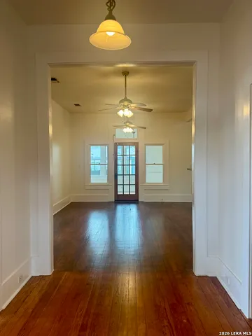 a view of an empty room with wooden floor and a window