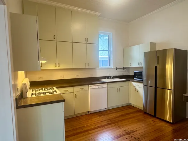 a kitchen with granite countertop stainless steel appliances a refrigerator a sink and cabinets