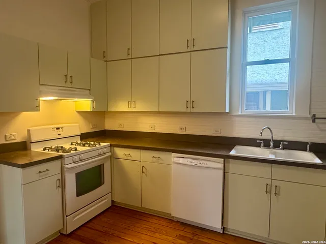 a kitchen with granite countertop white cabinets and white appliances