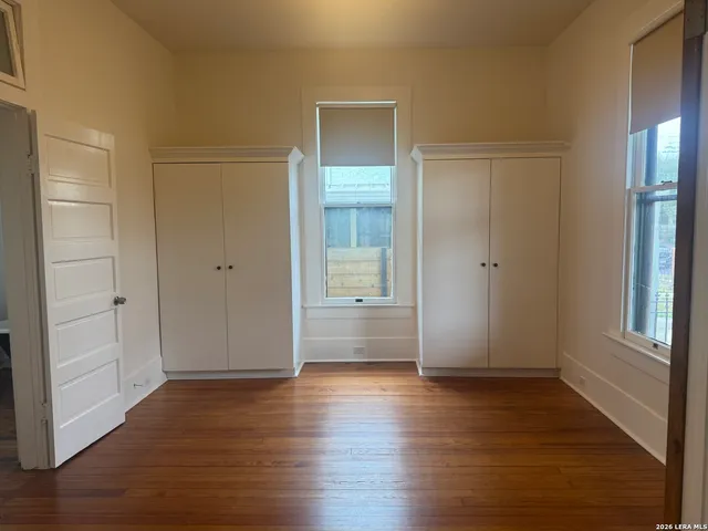 an empty room with wooden floor & windows