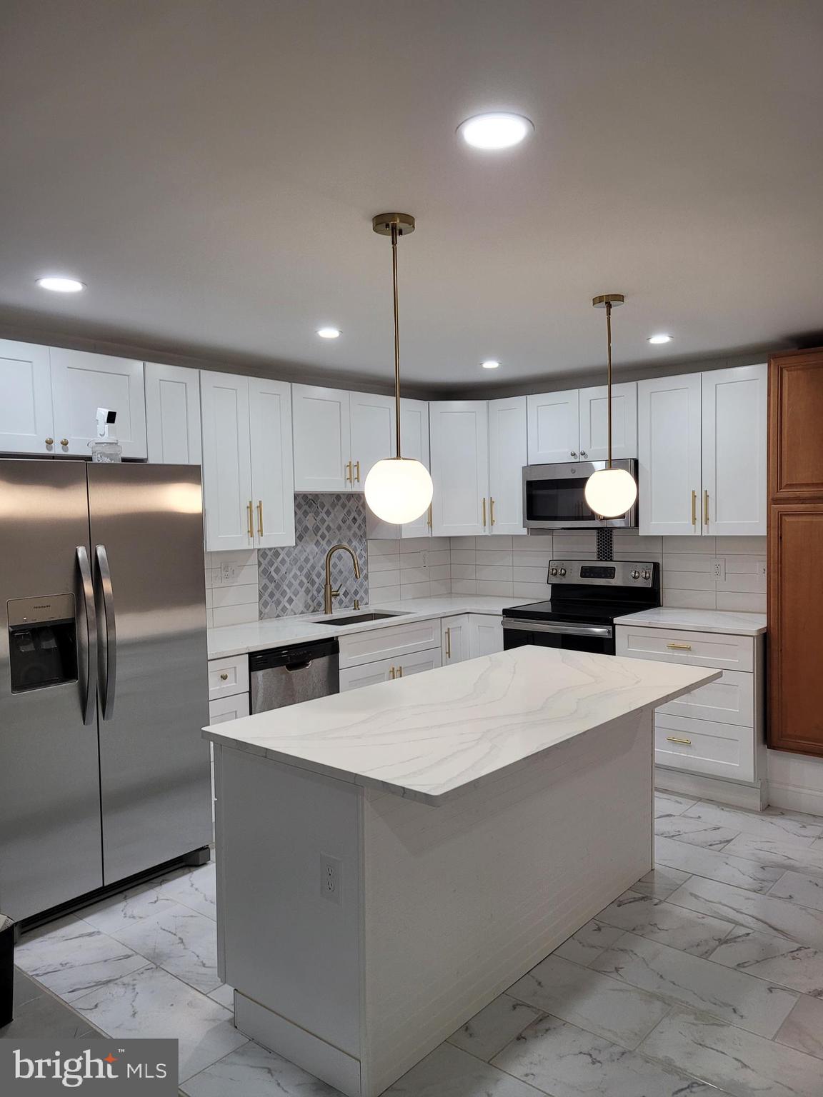 a large kitchen with a chandelier stainless steel appliances and a counter space