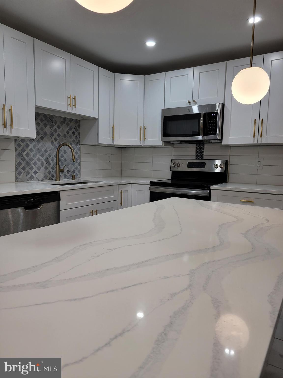 2502 Federal Street Philadelphia, PA 19146 - Photo 2 of 31 a kitchen with stainless steel appliances granite countertop a stove a refrigerator a sink dishwasher and white cabinets with wooden floor