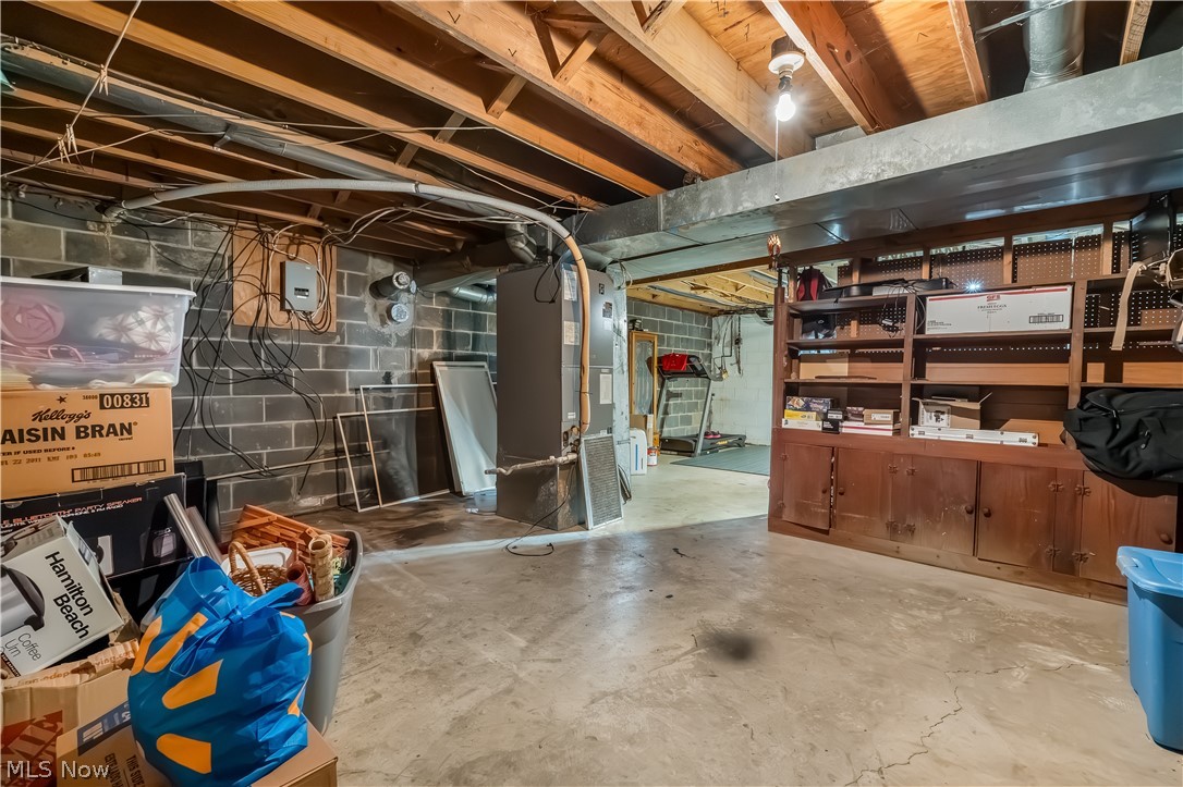 4922 South Ridge Road East Geneva, OH 44041 - Photo 28 of 46 Functional utility and storage area with built-in wooden shelving, offering exceptional organizational capacity or the blueprint for a future finished room.