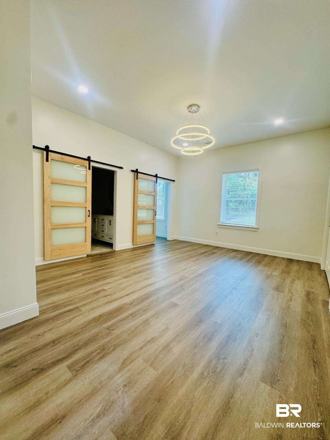 2663 Demetropolis Road Mobile, AL 36693 - Photo 15 of 26 Unfurnished living room featuring a barn door, wood finished floors, and a chandelier