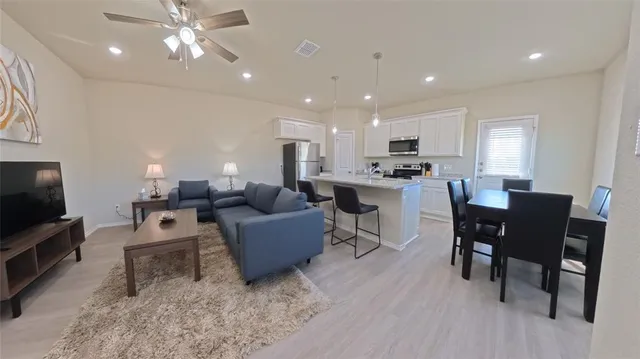 a kitchen with stainless steel appliances granite countertop a table chairs sink refrigerator and cabinets