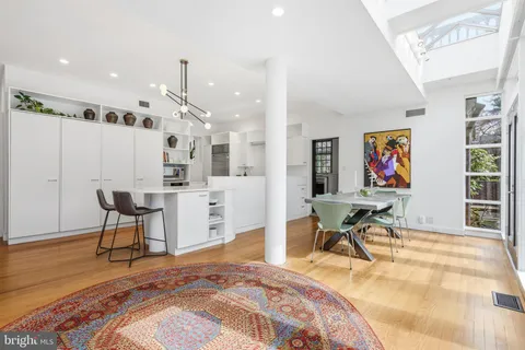 a kitchen with stainless steel appliances kitchen island granite countertop a table chairs and white cabinets