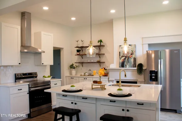 a kitchen with stainless steel appliances kitchen island granite countertop a sink a stove and a refrigerator