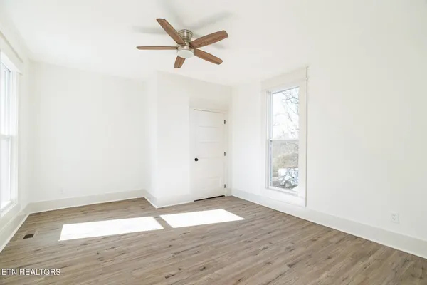 an empty room with wooden floor and windows