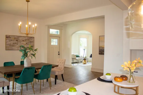 a view of a dining room with furniture one side kitchen view and wooden floor