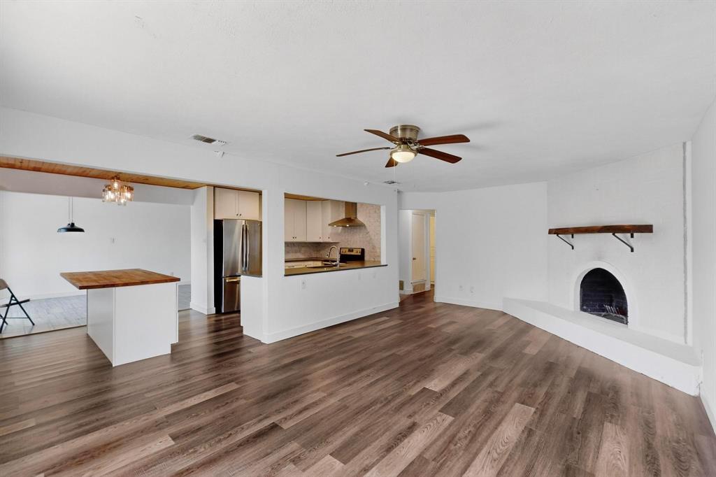 4857 Fallon Place Dallas, TX 75227 - Photo 6 of 19 Unfurnished living room with a chandelier, ceiling fan, a fireplace, and dark wood-style flooring