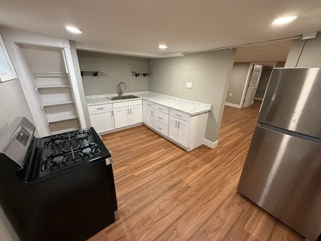a kitchen with granite countertop a refrigerator a sink and wooden floor