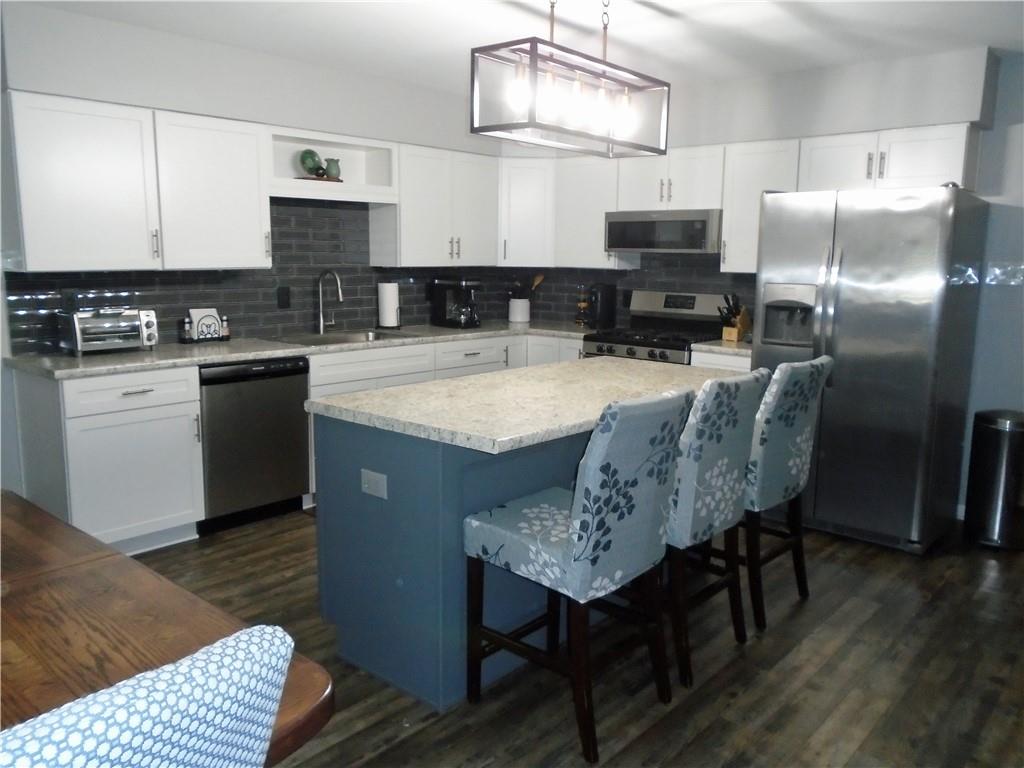480 Heller Street Rochester, PA 15074 - Photo 7 of 31 a kitchen with stainless steel appliances granite countertop a sink dishwasher a stove a refrigerator a microwave oven with a dining table and chairs