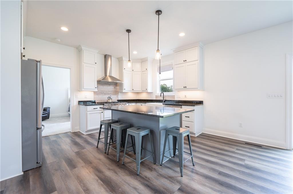 356 Stone Church Road Hunker, PA 15639 - Photo 7 of 40 a kitchen with kitchen island a stove a chandelier and a wooden floor