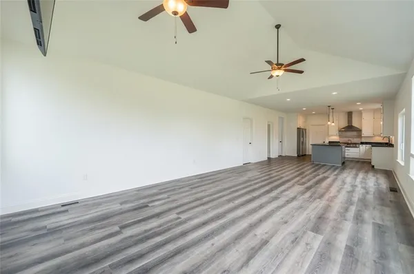 a view of empty room with wooden floor and ceiling fan