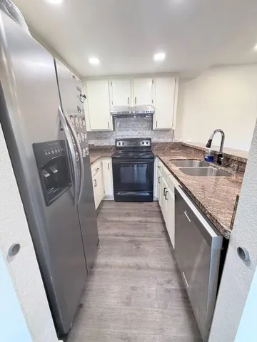 a kitchen with granite countertop a sink stove and refrigerator