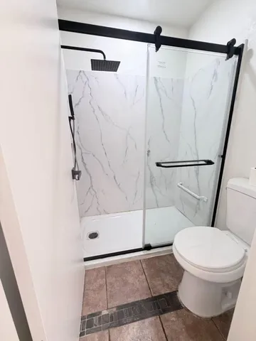 a white toilet sitting next to a shower