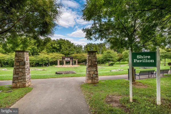 a view of a park that has a sign board large trees