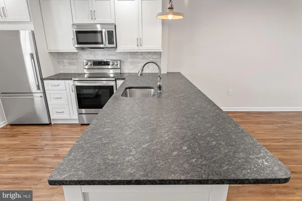 a kitchen with stainless steel appliances granite countertop a sink a stove top oven a refrigerator and white cabinets