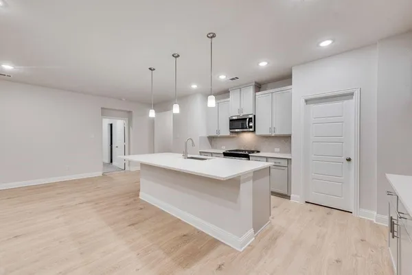 a kitchen with stainless steel appliances kitchen island a sink a stove a refrigerator and white cabinets