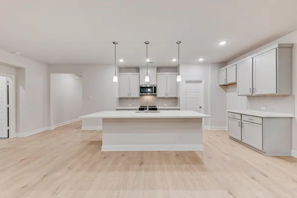 a large white kitchen with kitchen island a sink white cabinets and stainless steel appliances