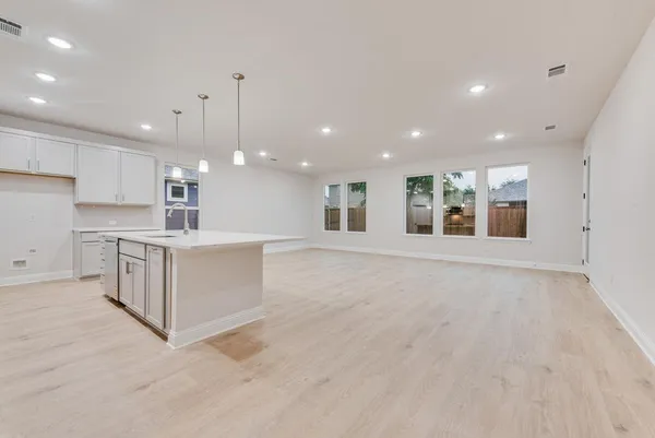 a large white kitchen with kitchen island a sink stainless steel appliances and cabinets