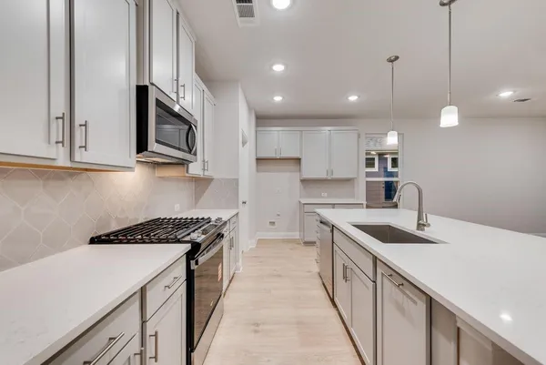 a kitchen with stainless steel appliances granite countertop a sink a stove and a wooden floors