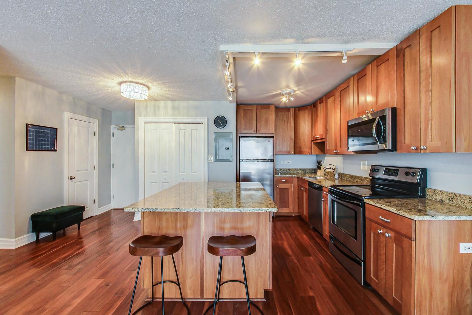2930 North Sheridan Road, Unit 811 Chicago, IL 60657 - Photo 23 of 52 a kitchen with granite countertop a stove a sink a refrigerator and wooden cabinets