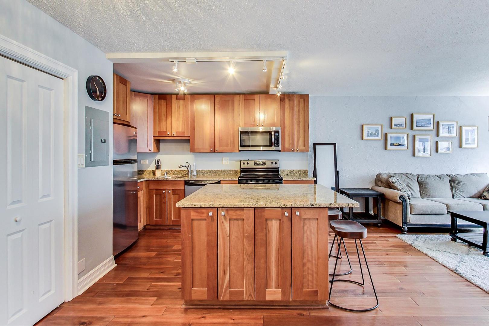 2930 North Sheridan Road, Unit 811 Chicago, IL 60657 - Photo 24 of 52 a kitchen with stainless steel appliances kitchen island granite countertop a refrigerator oven a sink dishwasher and white cabinets with wooden floor