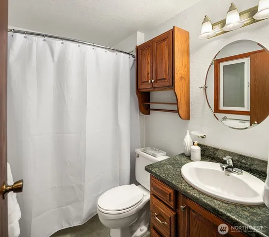a bathroom with a granite countertop sink a toilet and a mirror