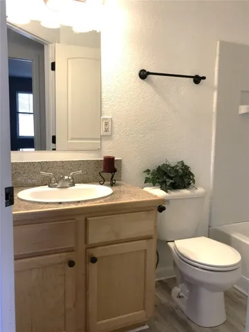 a bathroom with a granite countertop toilet sink and mirror