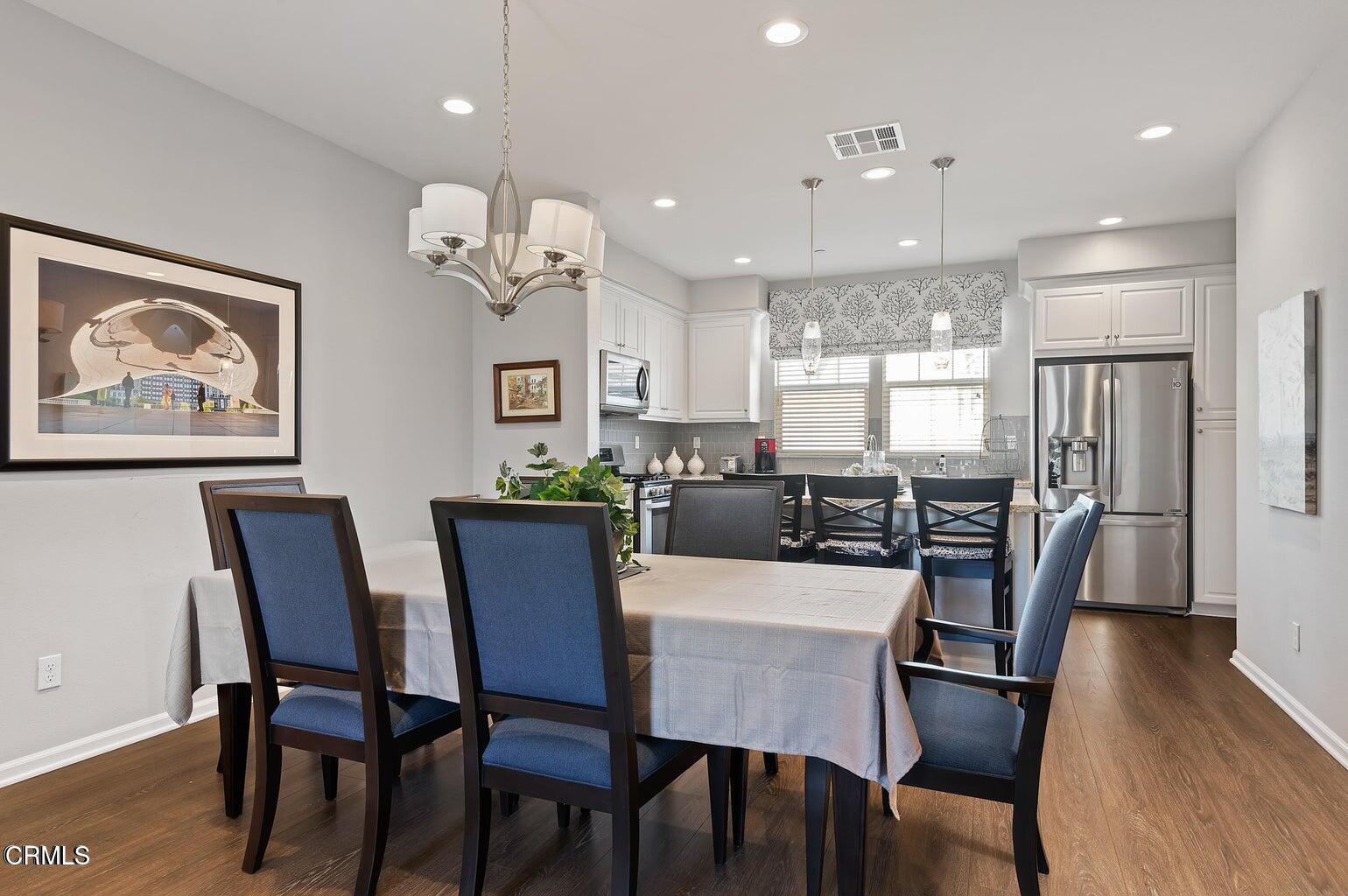 3661 West Hemlock Street Oxnard, CA 93035 - Photo 7 of 21 a dining room with wooden floor a chandelier a wooden table and chairs