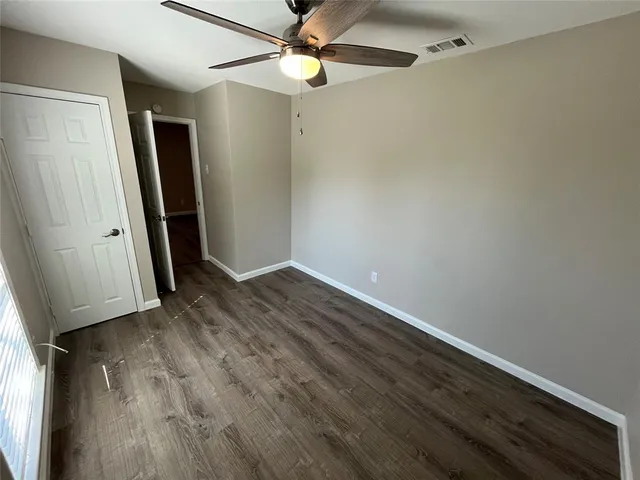 an empty room with wooden floor a ceiling fan and closet