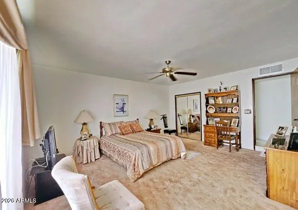 a bedroom with a bed and a large mirror on the dresser