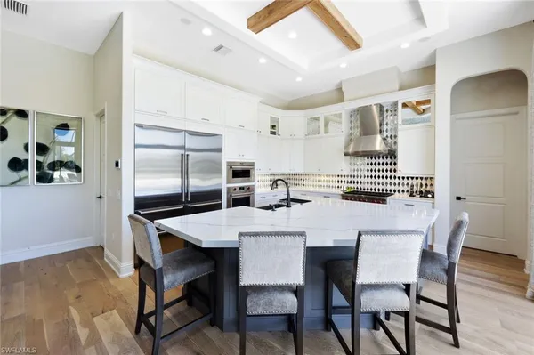 a kitchen with stainless steel appliances kitchen island granite countertop a dining table chairs and a refrigerator