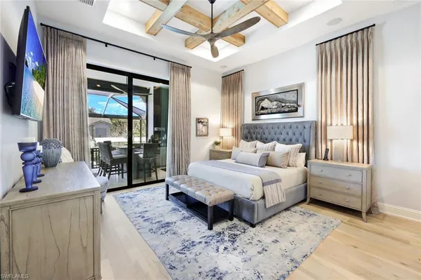 a bedroom with a bed a mirror and a flat tv screen on dresser