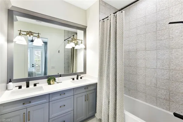 a bathroom with a double vanity sink mirror and bathtub