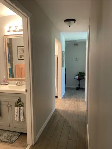 a view of a hallway with wooden floor and a bathroom