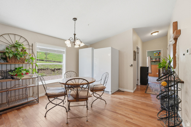 8066 North Valley View Heights Preston, ID 83263 - Photo 16 of 34 Dining area featuring wood-finish flooring, a window with a landscape vista, and a ceiling-mounted light fixture