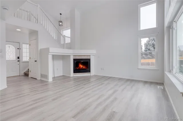 an empty room with wooden floor a fireplace and windows