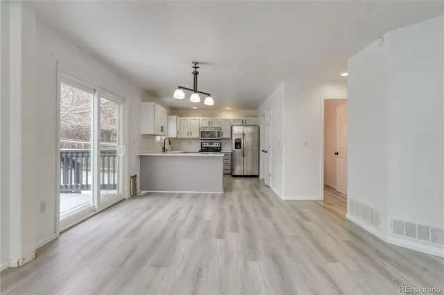 a view of a kitchen with a sink and dishwasher a refrigerator with wooden floor
