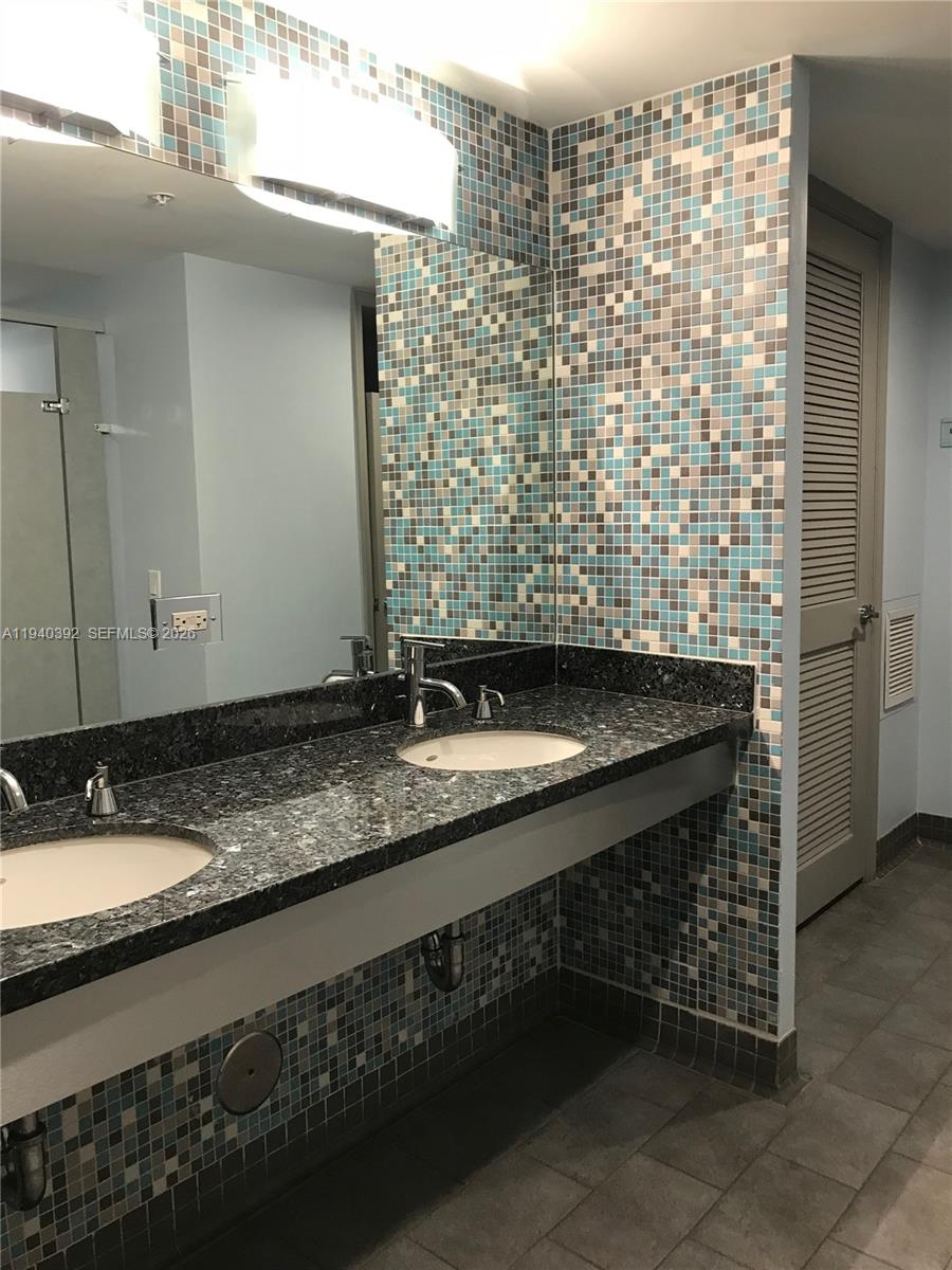 480 Northeast 30th Street, Unit 1403 Miami, FL 33137 - Photo 25 of 30 a bathroom with a granite countertop sink a mirror and shower