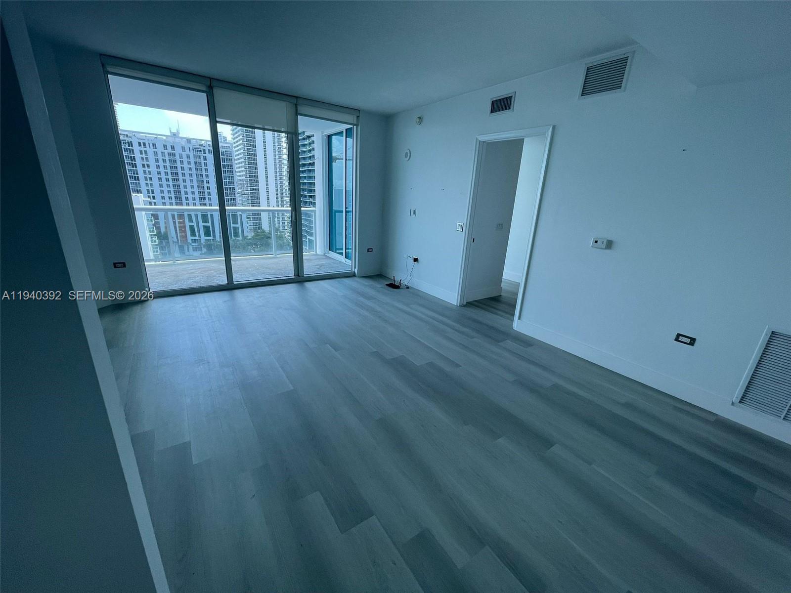 480 Northeast 30th Street, Unit 1403 Miami, FL 33137 - Photo 5 of 30 an empty room with wooden floor and windows