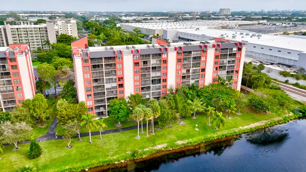 a aerial view of multi story residential apartment building with yard and parking spaces