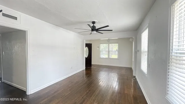 a view of empty room with wooden floor and fan
