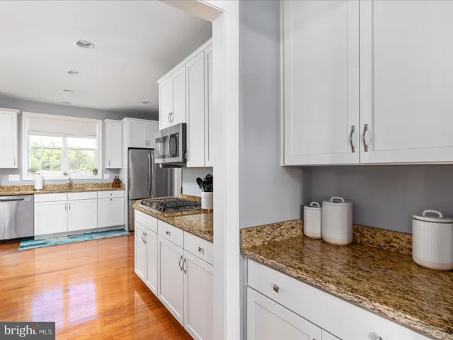a large kitchen with a lot of counter space and wooden floor